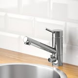 Modern chrome kitchen faucet with pull-out sprayer on wooden countertop, featuring water and energy-saving aerator.