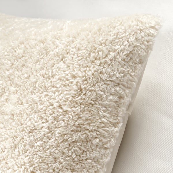 Lähikuva pehmeästä, kermanvärisestä nalletyynynpäällisestä, jossa on vetoketjullinen yksityiskohta.