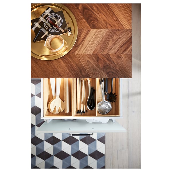 Moderni keittiötaso puisella chevron-kuviolla. Se erilaisia ruoanlaittovälineitä laatikoissa ja tyylikkäitä tarvikkeita päällä.