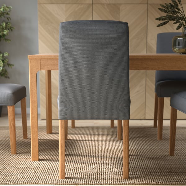 Kolme harmaata pehmustettua tuolia puisen pöydän ympärillä, joissa on irrotettavat, pestävät päälliset ja puiset jalat.