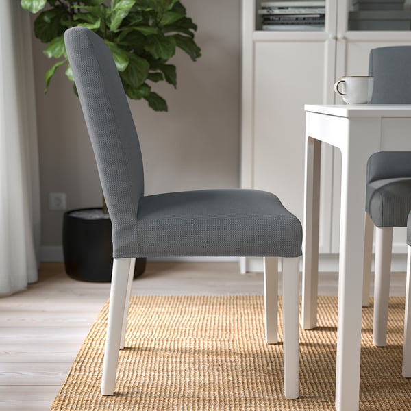 Moderni ruokailutila, jossa on harmaa pehmustettu tuoli, valkoiset jalat ja pieni valkoinen pöytä.