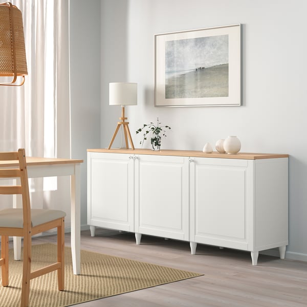 Moderni olohuone, jossa on BESTÅ-senkki, lamppu, kasvi, rantaprintti, valkoinen tuoli.