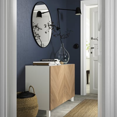 Moderni BESTÅ-senkki vaaleasta tammesta, sininen seinä, peili, lamppu, kori, maljakko oksilla, kirjat, kultainen pallo, pehmeästi sulkeutuvat saranat.