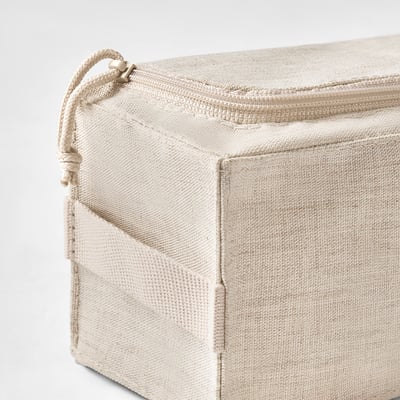 Beige BOLLÖSUND-säilytyslaatikko, joka on valmistettu uusiutuvista materiaaleista. Se on suorakaiteen muotoinen, vetoketjulla ja pienellä kahvalla toisessa päässä.