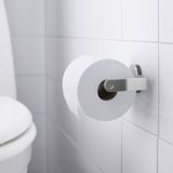 Valkoinen wc-paperiteline, joka on kiinnitetty valkoiselle kaakeloidulle seinälle, jossa on wc-paperirulla, osa BROGRUND-sarjaa piiloruuveilla.