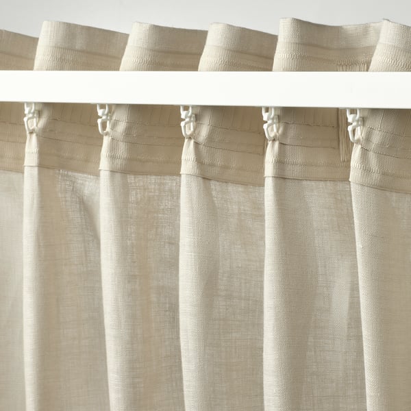 Beige-pellavaverhot otsikkoteipillä ja koukuilla laskostettuun ripustamiseen.