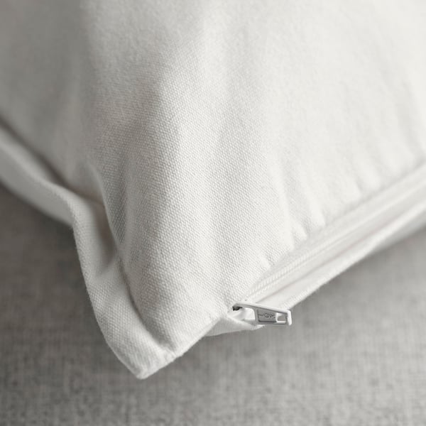 Lähikuva valkoisesta, hienosti kuvioidusta puuvillaisesta tyynynpäällisestä, jossa on piilotettu vetoketju, joka esittelee sen laatua ja muotoilua.