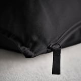 Lähikuva: musta tyynynpäällinen laadukkaalla vetoketjulla, kuvioitu kangas, todennäköisesti puuvillaa.