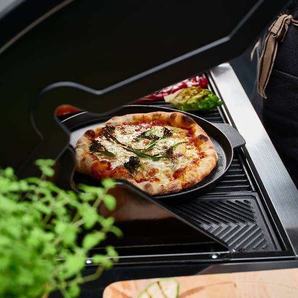 Tuoretta pizzaa valurautapannulla grillillä. Kahvat helppoon nostamiseen, rapeaan pintaan.