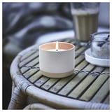 Keraaminen kynttilä valkoisena, jossa on pilkkuja pajupöydällä, valaistu suolapurkilla vieressä.