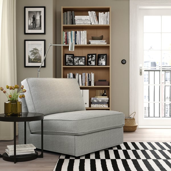 Moderni olohuone, jossa harmaa KIVIK-sohva, kirjahylly ja raidallinen matto.