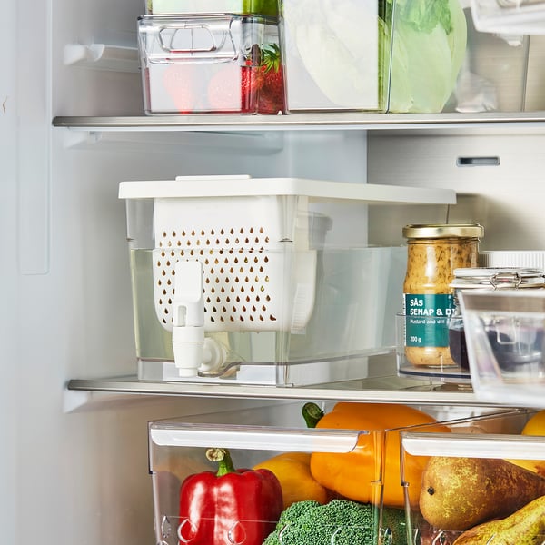 Avoin jääkaappi vihanneksilla, purkilla ja läpinäkyvällä laatikolla, jossa on KLIPPKAKTUS-hana jäähdytetyille juomille.