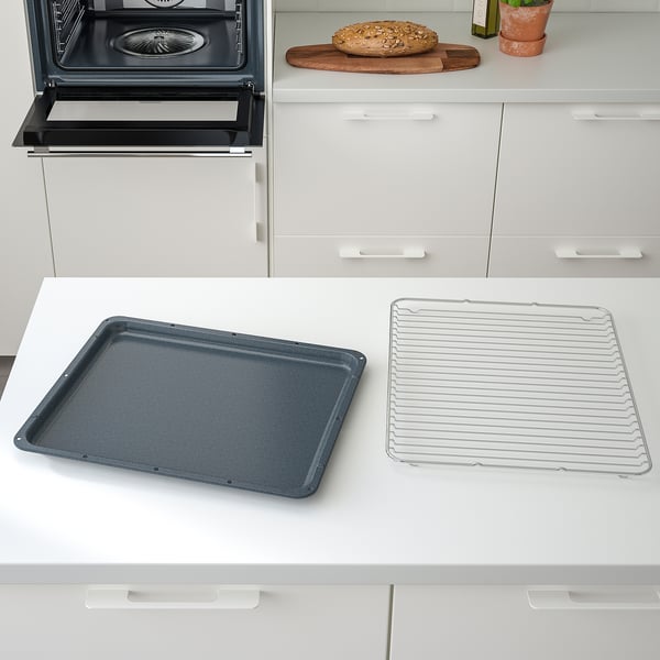 Moderni keittiökohtaus: avoin uuni, uunipelti, ritilä tiskillä.