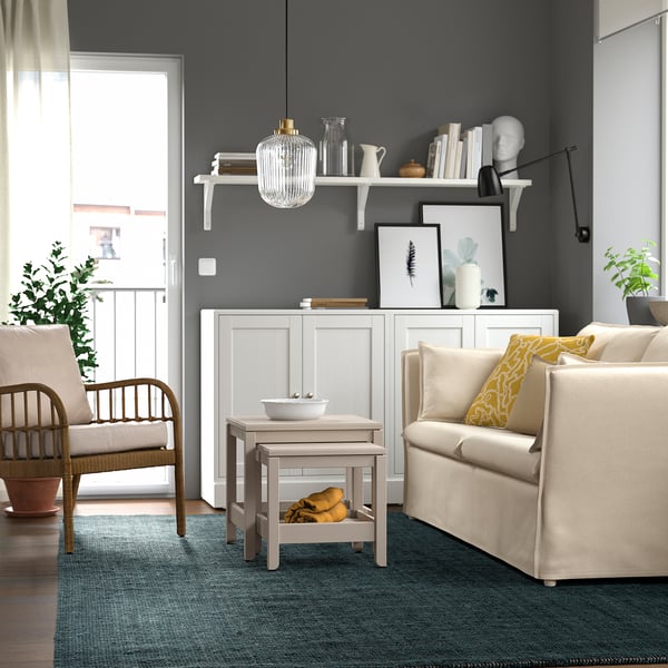 Moderni olohuone, jossa on LANDBANA-juuttimatto, kaksi nojatuolia, sohva ja sisustus harmailla seinähyllyillä, jotka luovat kodikkaan tunnelman.