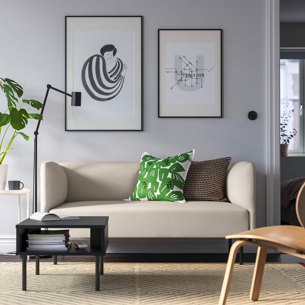 Painopiste: LILLEHEM beige moduulisohva, harmaa seinä, vihreät tyynyt, musta sohvapöytä, puinen tuoli, modernin taiteen printit.