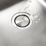 Ruostumattomasta teräksestä valmistettu pesualtaan kansi magneettisella pohjalla, hajallaan olevat vesipisarat, puhdas tasainen pinta.