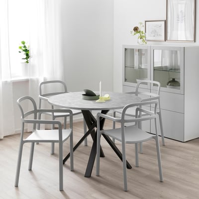 Pyöreä moderni ruokapöytä, jossa on 4 harmaata tuolia, ihanteellinen kompakteihin tiloihin. Keskitetty tarjotin kynttilällä.