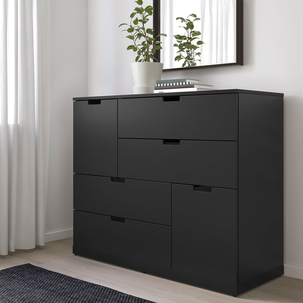 Moderni musta NORDLI-lipasto 6 laatikolla, ikkunan vieressä, pieni kasvi päällä.