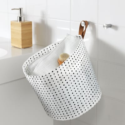 Valkoinen pilkullinen roikkuva kylpyhuonelaatikko, jonka sisällä on suihkuharja.