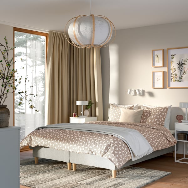 Moderni makuuhuone king bed -sängyllä, kevyt sisustus, abstraktit valot, yöpöydät.