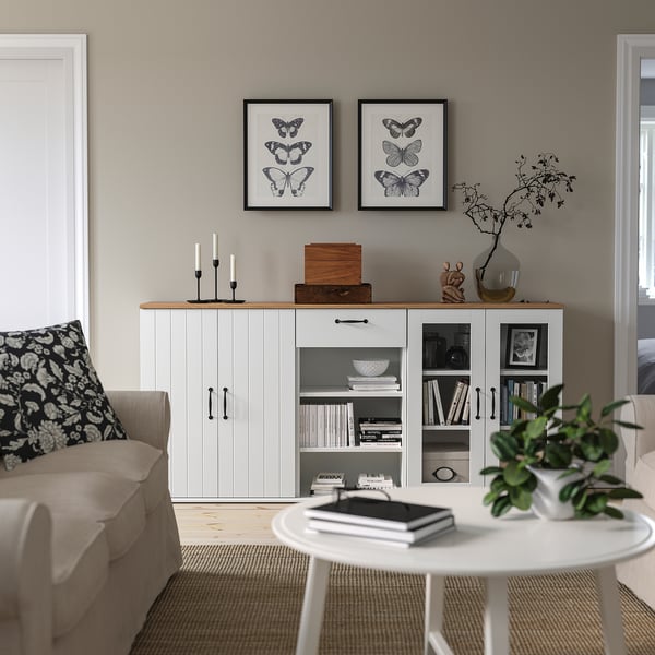 Moderni olohuone, jossa on SKRUVBY-senkki, perhostosia, beige sohva ja pyöreä sohvapöytä, jossa on kirjoja ja kasveja.