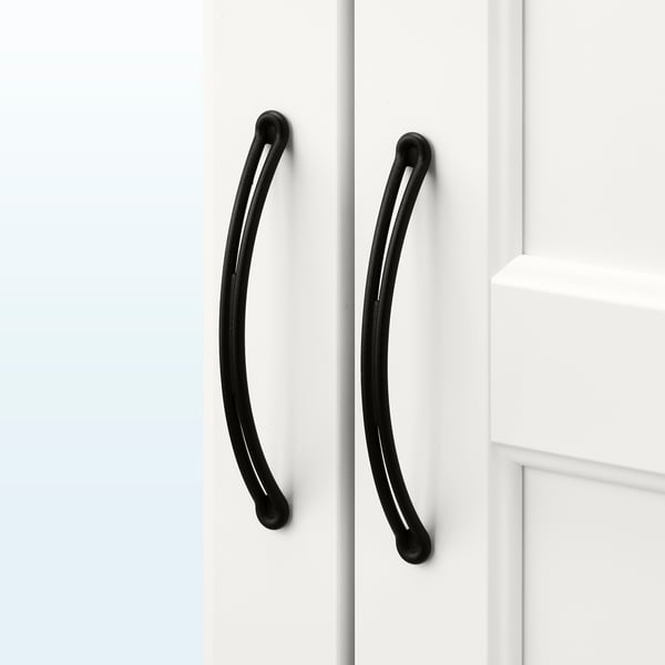 Mustat kaarevat kahvat valkoisissa kaappien ovissa, tyylikäs ja minimalistinen muotoilu.