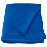 Kirkkaan sininen villapeitto siististi taitettuna, pehmeä tuntuinen, suorakaiteen muotoinen, selkeät linjat, skandinaavinen muotoilu.