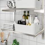 Keittiön hylly, jossa on järjestäjä, jossa säilytetään pulloja, kuppeja, pyyhkeitä ja ruokailuvälineitä siististi.