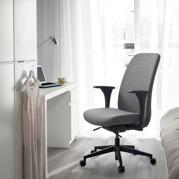 Minimalistinen harmaa VALLFJÄLLET-työtuoli pienen työpöydän ääressä, kannettava tietokone ja kahvi.