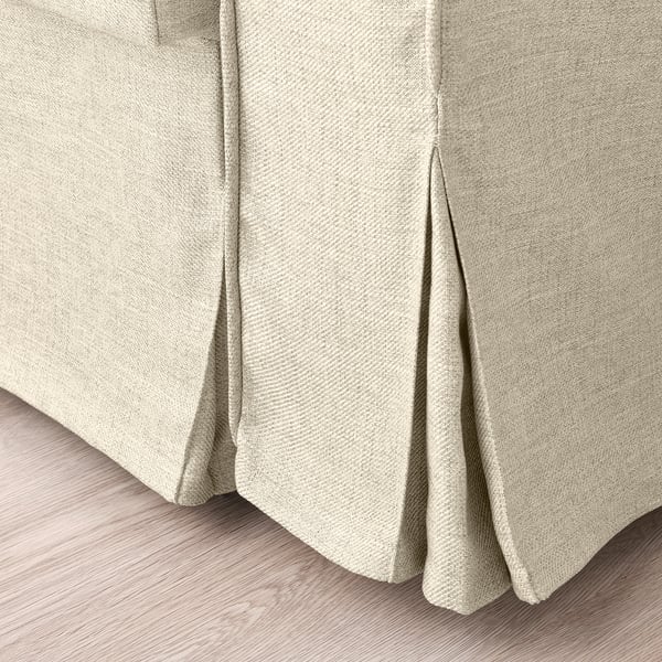 Pehmeä, beige vuodesohvakangas lähikuvassa. Näyttää sileän, kuvioidun kudoksen ja siistit ompeleet.