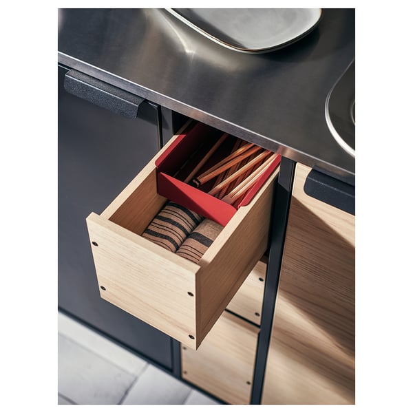 Modern kökslåda öppen, röda handtag, träbestick, slät yta.