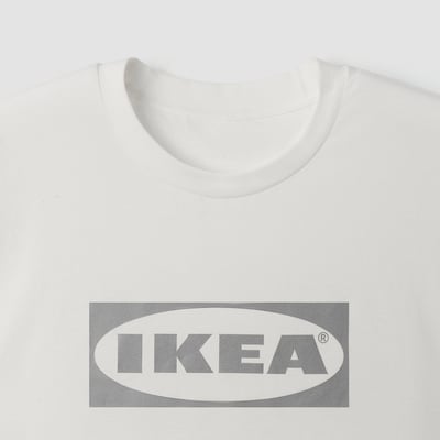 En vit t-shirt av hög kvalitet från IKEA, med en framträdande grå IKEA-logotyp på framsidan. Den är gjord av mjuk bomull, perfekt för komfort.