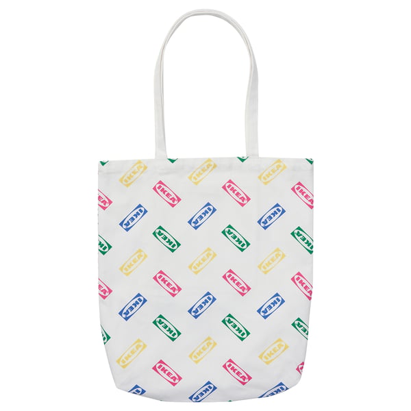 Vit tygkasse med färgglada IKEA-logotyper, bomullsmaterial, rektangulär form, långa handtag.