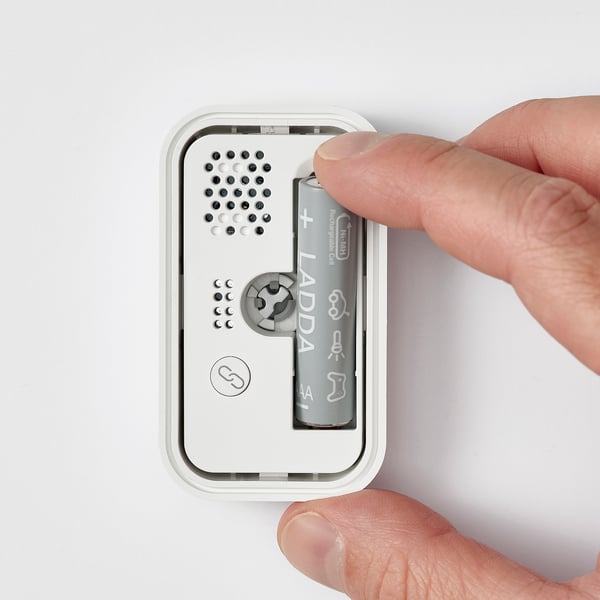 Person som placerar batteriet i BADRING vattenläckagesensor, vilket säkerställer att det är redo att upptäcka läckor och skicka meddelanden via dirigera hubben.