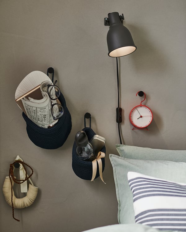 Sängkrokar: BÄNGBULA, svart, stål, oval form, väggfäste. Röd klocka, lampa, randig kudde.