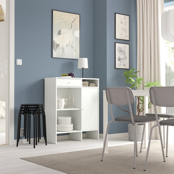 Modern matplats med vit förvaring BAGGEBO, grå stolar och blå väggar. Dekorerad med tryck och växter.