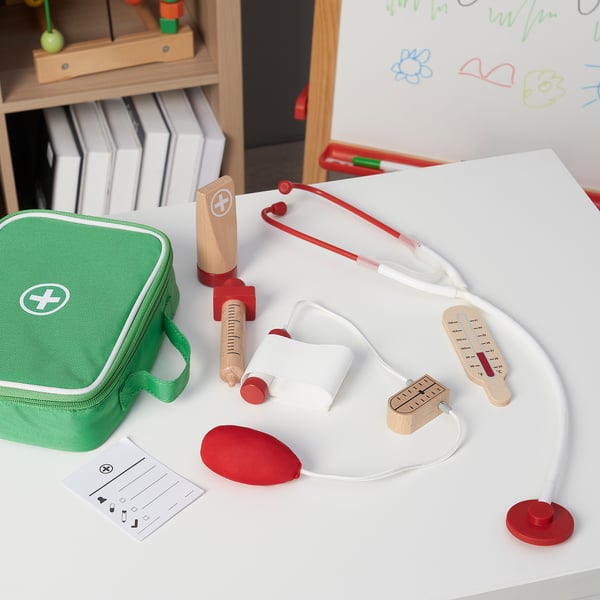 Leksaksset med stetoskop, termometer och spruta på bordet med grön påse.