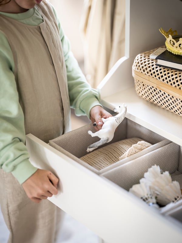 Kvinna som packar upp BAXNA grå organisatör från låda, beige och grädde toner.