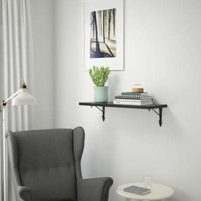 Myshörna med stol, böcker, växt, lampa och skogstryck.