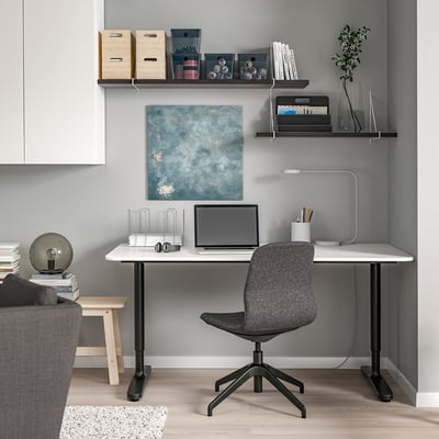 Modernt hemmakontor: vitt BERGSHULT skrivbord, grå stol, vägghyllor med böcker och laptop.