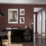 Modern matsal med mörkröda väggar, svart skänk och inredning.