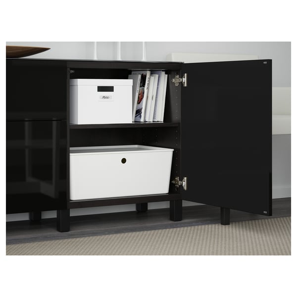 Svart träskåp med glasskiva, två lådor och hyllor, organiserade med vita förvaringsbehållare.