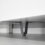 Benstöd i svart metall gömda under vita möbler, vilket förbättrar stabiliteten.