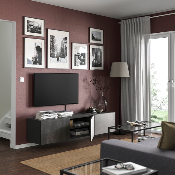 Modernt vardagsrum med rödbruna väggar, svart tv-bänk BESTÅ, grå soffa och stort fönster.