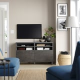 Vardagsrum med modern decentraliserad underhållning, med svart BESTÅ-tv-bänk, plattskärm, blå soffa och inredning.