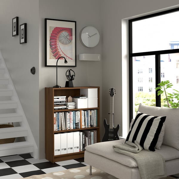 Mysig hörna med BILLY bokhylla, böcker, media, randig kuddsoffa, lutande gitarr, klocka, konst, högtalare, rutig golvtrappa.
