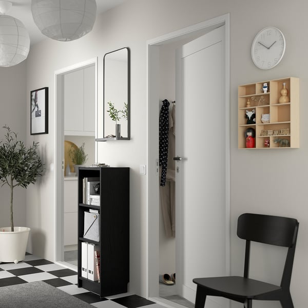 Modern entré med BILLY-bokhylla, spegel, krukväxt, stol, klocka, hyllor och hängande rockar.