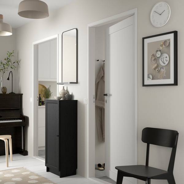 Modern entré med svart BILLY-kabinett, vita väggar och piano.