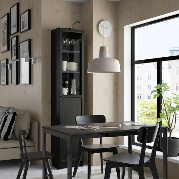 Modern matsal med svart bord, stolar, BILLY-skåp, lampa, klocka, soffa, växt.