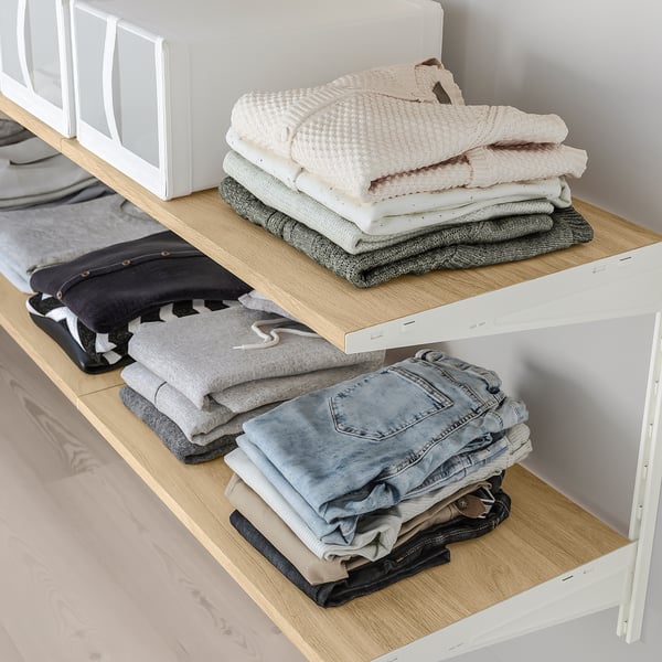 Vikta kläder i garderoben: tröjor upptill, jeans/byxor nedtill, flyttbara hyllplan.